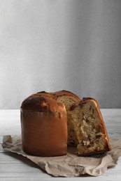 Delicious cut Panettone cake with raisins on white wooden table. Traditional Italian pastry
