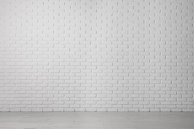 Photo of Beautiful white brick wall and wooden floor in clean empty room
