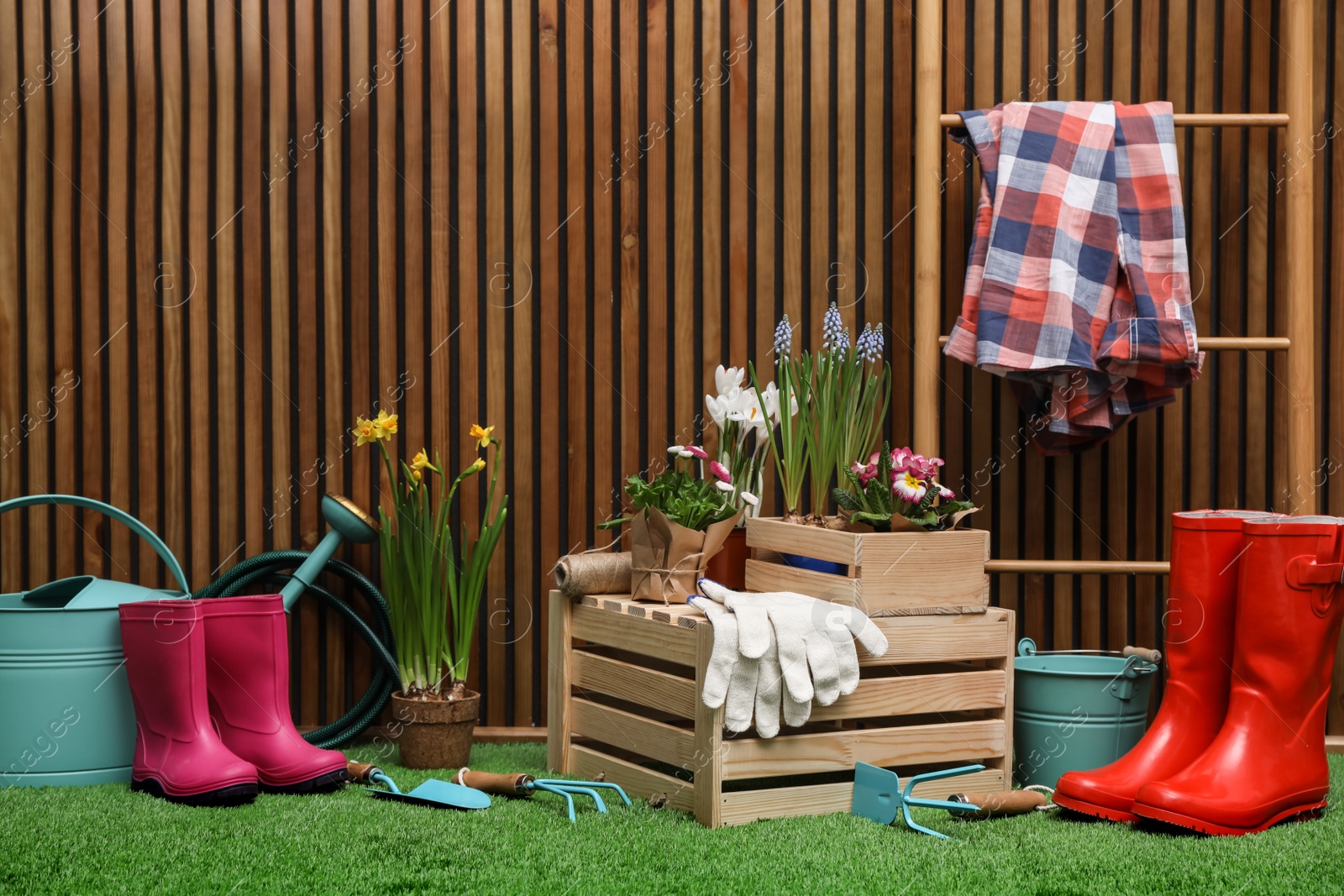 Photo of Composition with different gardening tools on artificial grass at wooden wall. Space for text