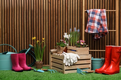 Photo of Composition with different gardening tools on artificial grass at wooden wall. Space for text