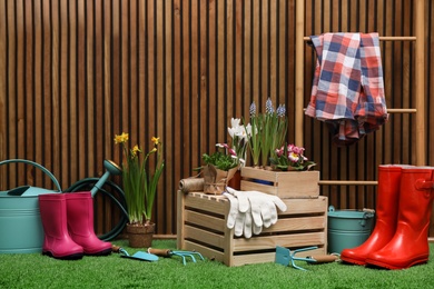 Composition with different gardening tools on artificial grass at wooden wall. Space for text