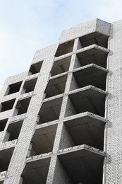Photo of Construction site with unfinished building under cloudy sky, low angle view