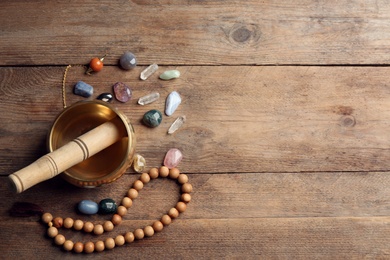 Flat lay composition with golden singing bowl on wooden table, space for text. Sound healing