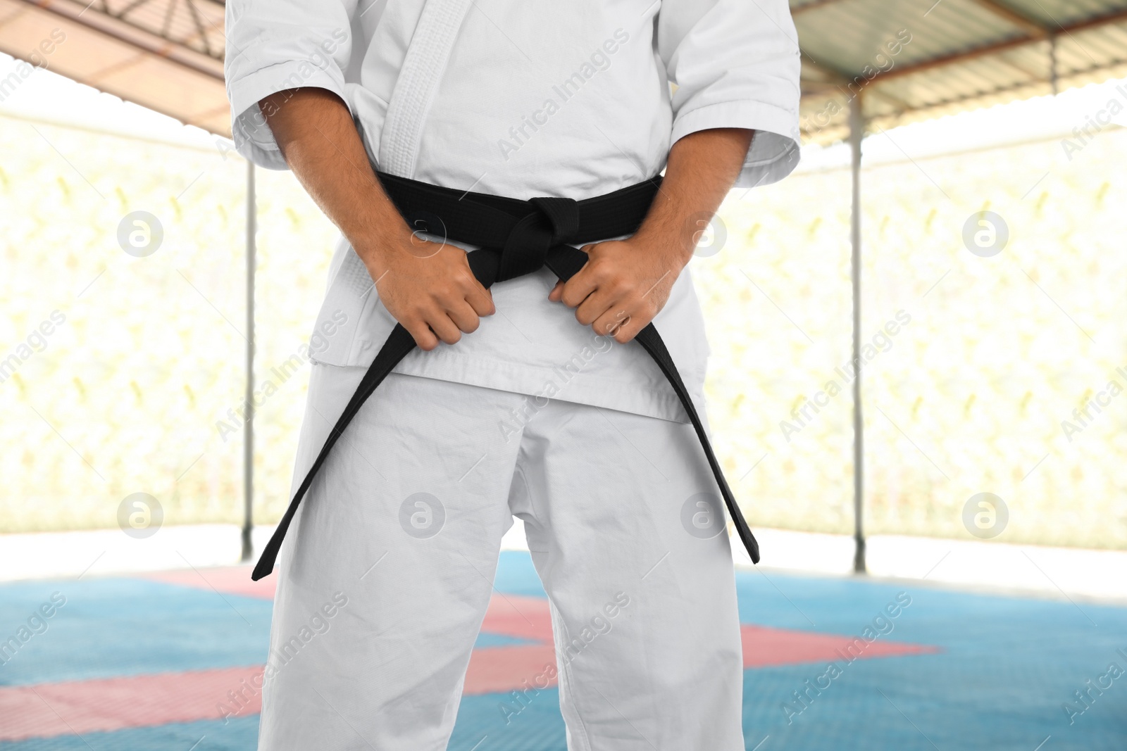 Photo of Karate coach wearing kimono and black belt at outdoor gym, closeup
