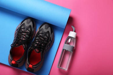 Photo of Sneakers, fitness mat and bottle of water on pink background, flat lay with space for text. Morning exercise