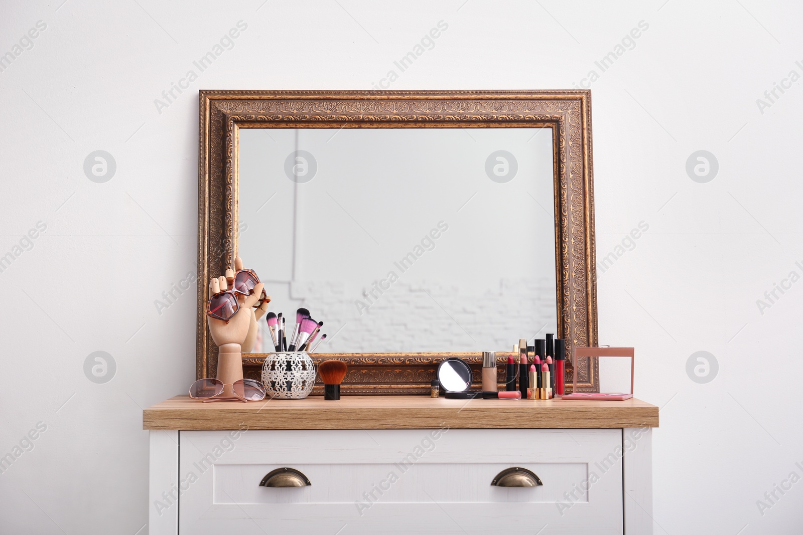 Photo of Makeup products and accessories near mirror on dressing table