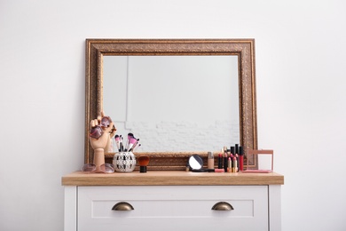 Makeup products and accessories near mirror on dressing table