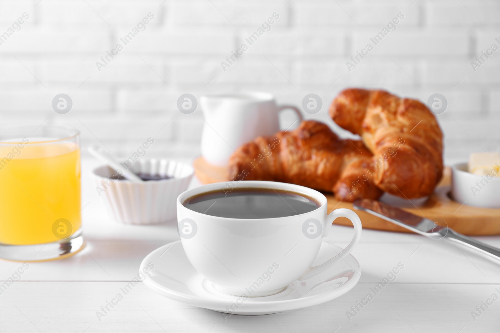 Photo of Fresh croissants, juice and coffee on white wooden table. Tasty breakfast