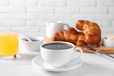 Fresh croissants, juice and coffee on white wooden table. Tasty breakfast