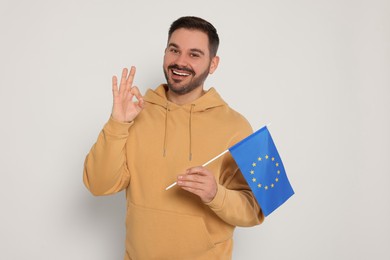 Photo of Man with flag of European Union showing ok gesture on white background