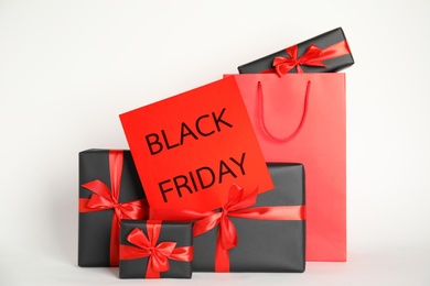 Photo of Many gifts and sheet of paper with words Black Friday on white background
