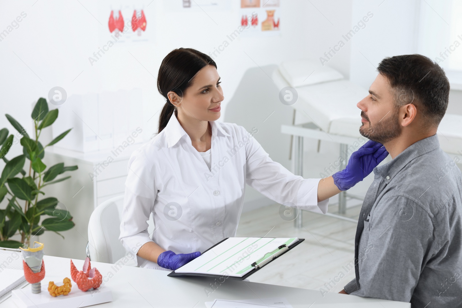 Photo of Endocrinologist examining thyroid gland of patient at table in hospital
