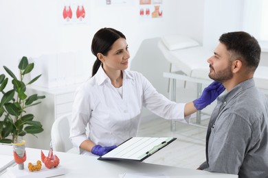 Endocrinologist examining thyroid gland of patient at table in hospital