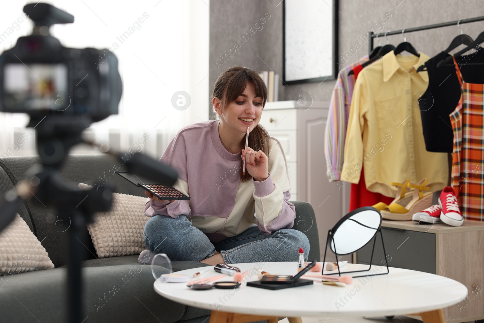 Photo of Smiling beauty blogger recording makeup tutorial at home