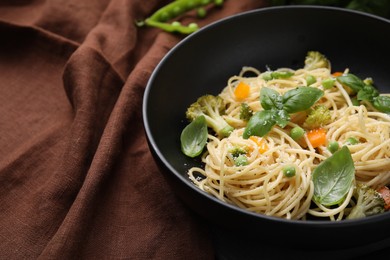 Photo of Delicious pasta primavera with basil, broccoli and peas on table, closeup. Space for text