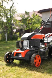 Modern lawn mower on green grass in garden