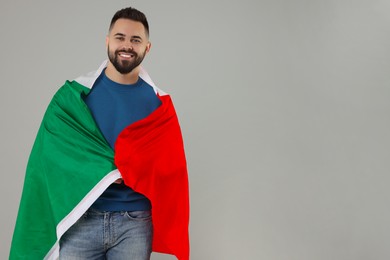 Young man with flag of Italy on light grey background, space for text