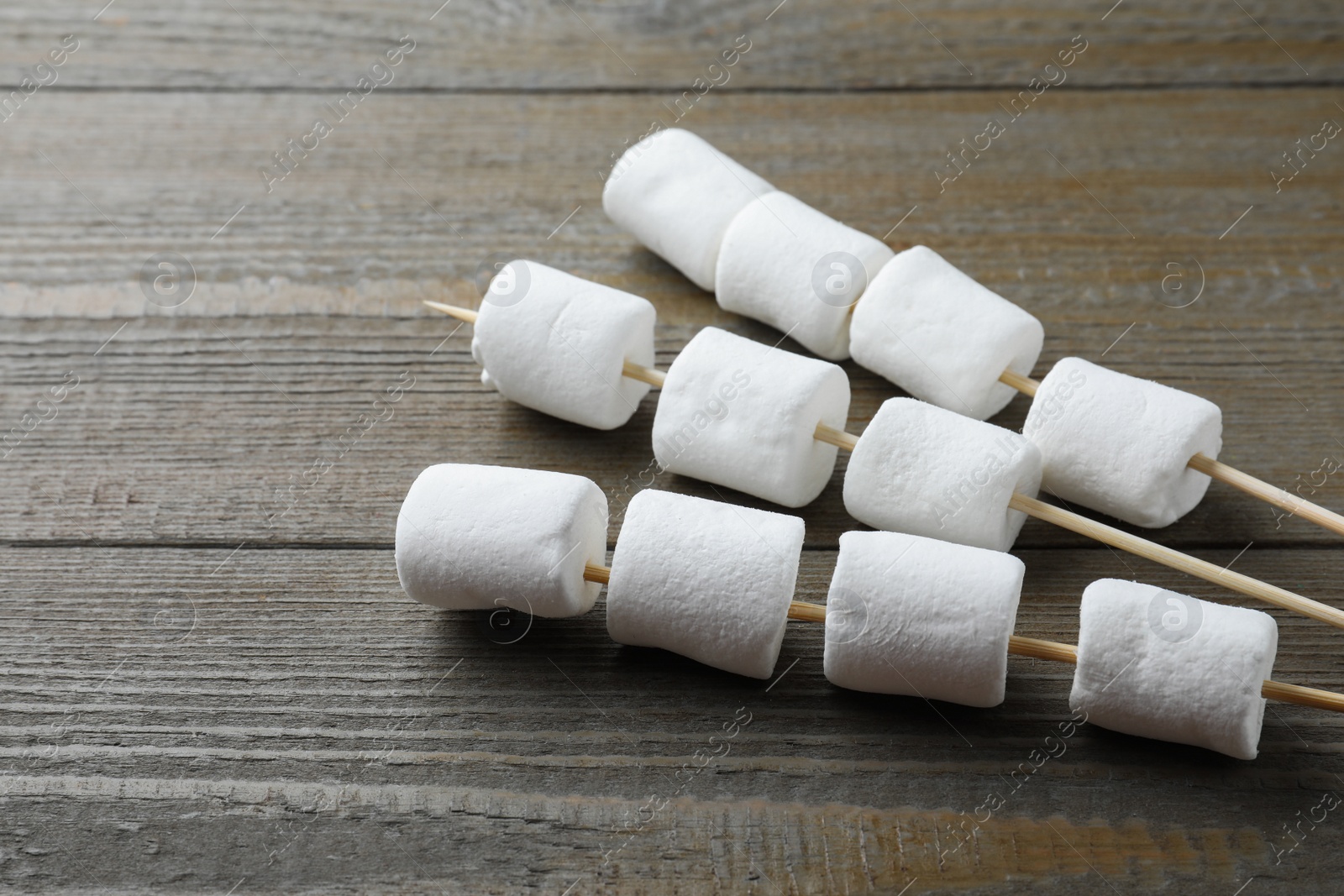 Photo of Sticks with sweet marshmallows on wooden table