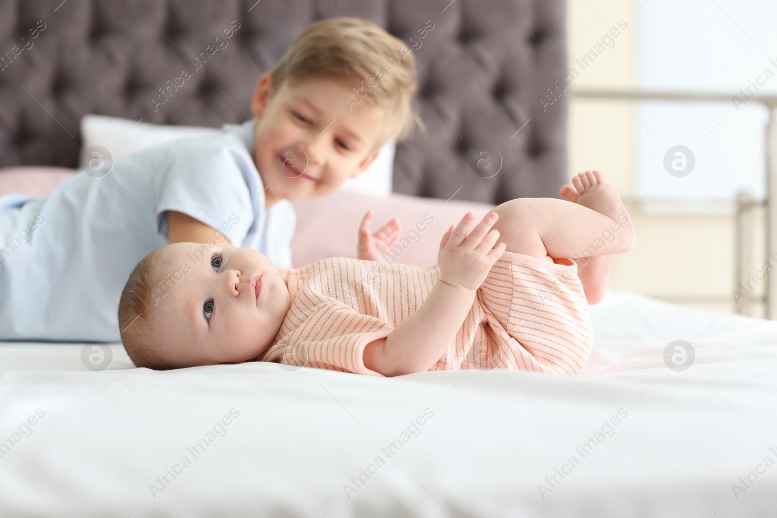 Photo of Cute little baby with elder brother lying on bed at home