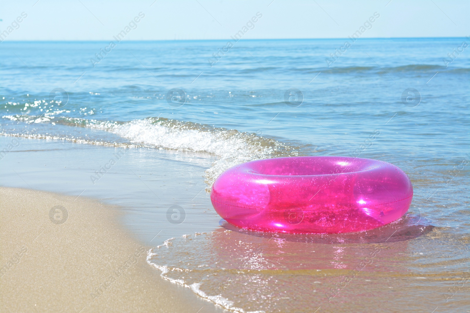 Photo of Bright inflatable ring on sandy beach near sea. Space for text