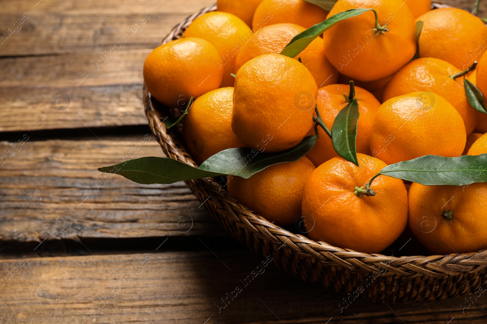 Photo of Fresh ripe tangerines with leaves on wooden table, closeup. Citrus fruit