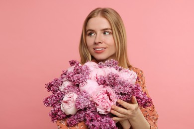 Beautiful woman with bouquet of spring flowers on pink background