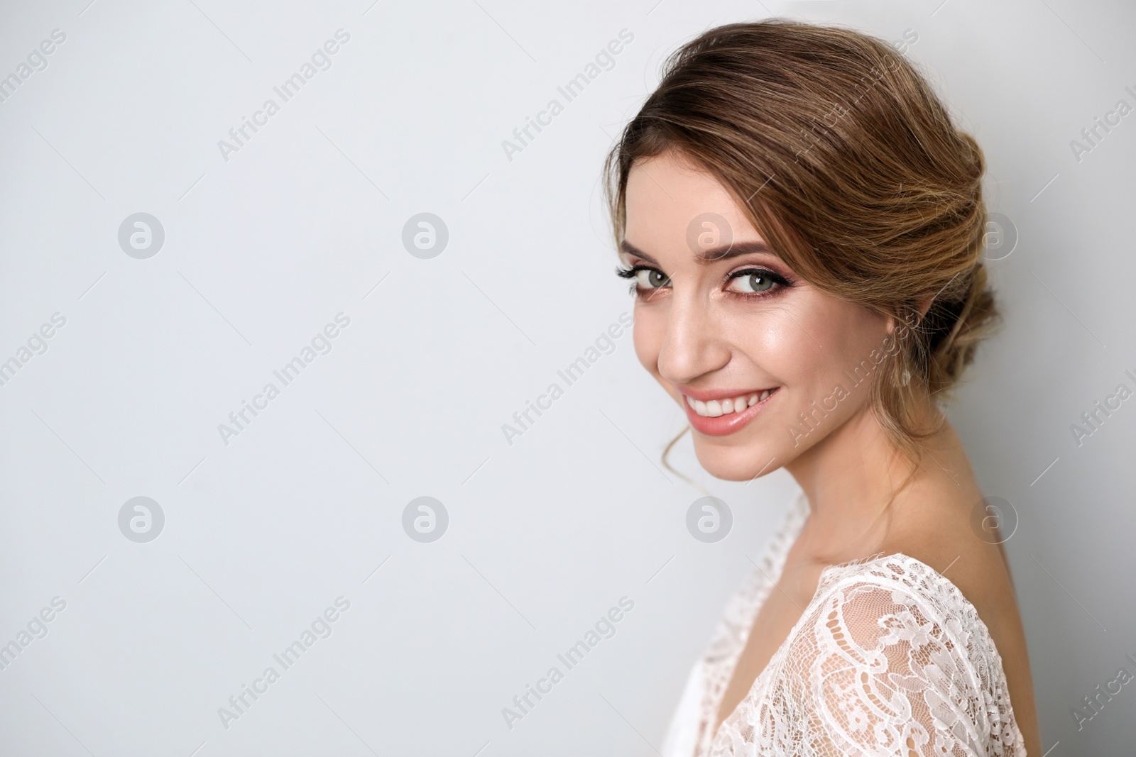 Photo of Young bride with elegant wedding hairstyle on light grey background. Space for text