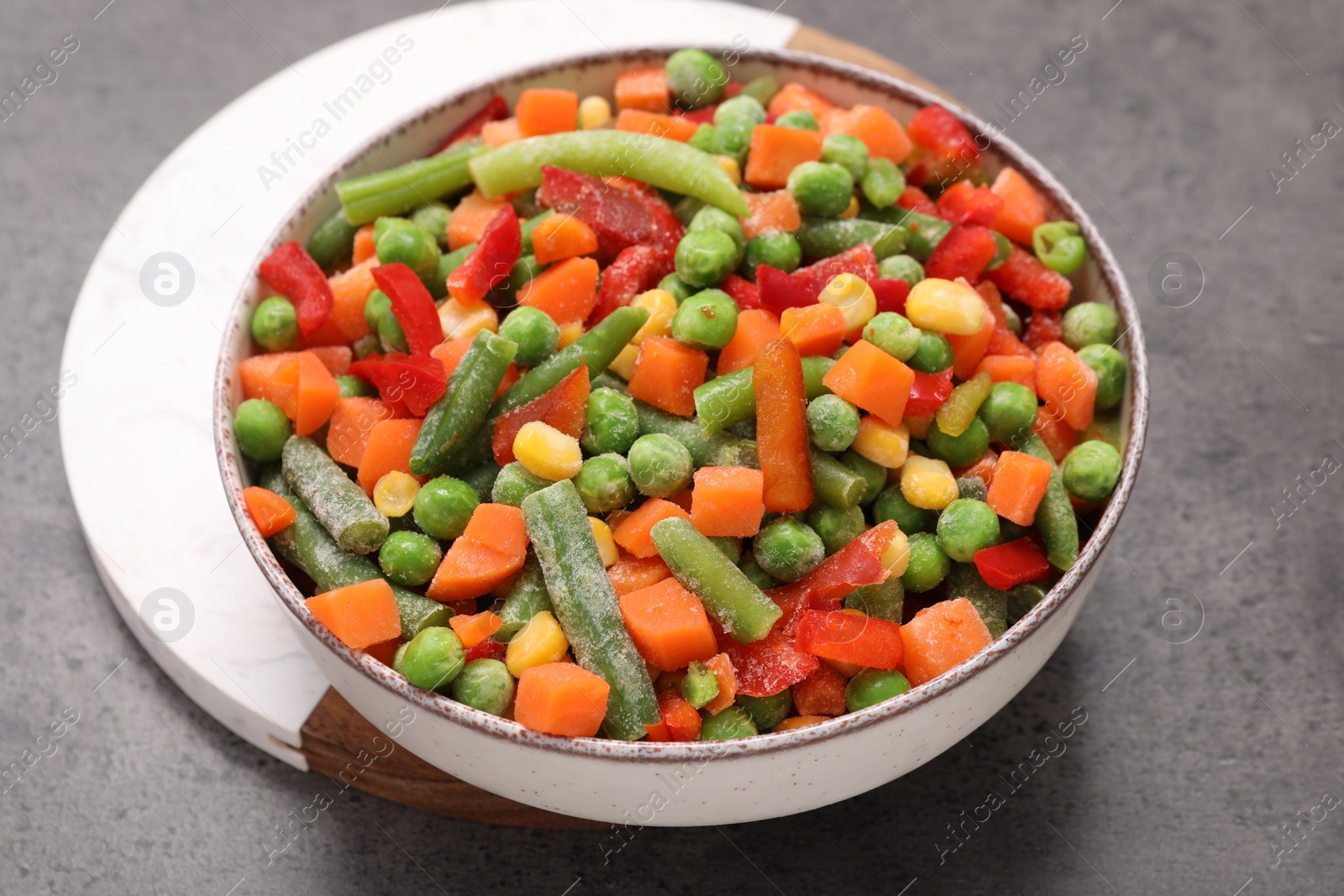 Photo of Mix of different frozen vegetables in bowl on grey table, closeup