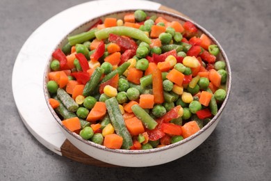 Photo of Mix of different frozen vegetables in bowl on grey table, closeup