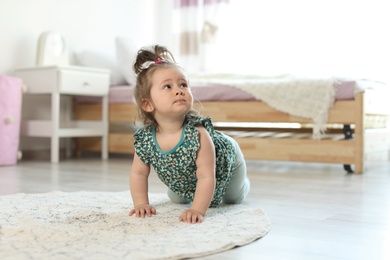 Adorable little baby girl crawling on floor in room