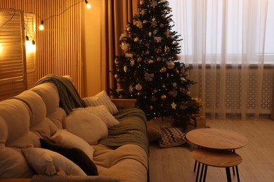 Comfortable furniture and Christmas tree in stylish room