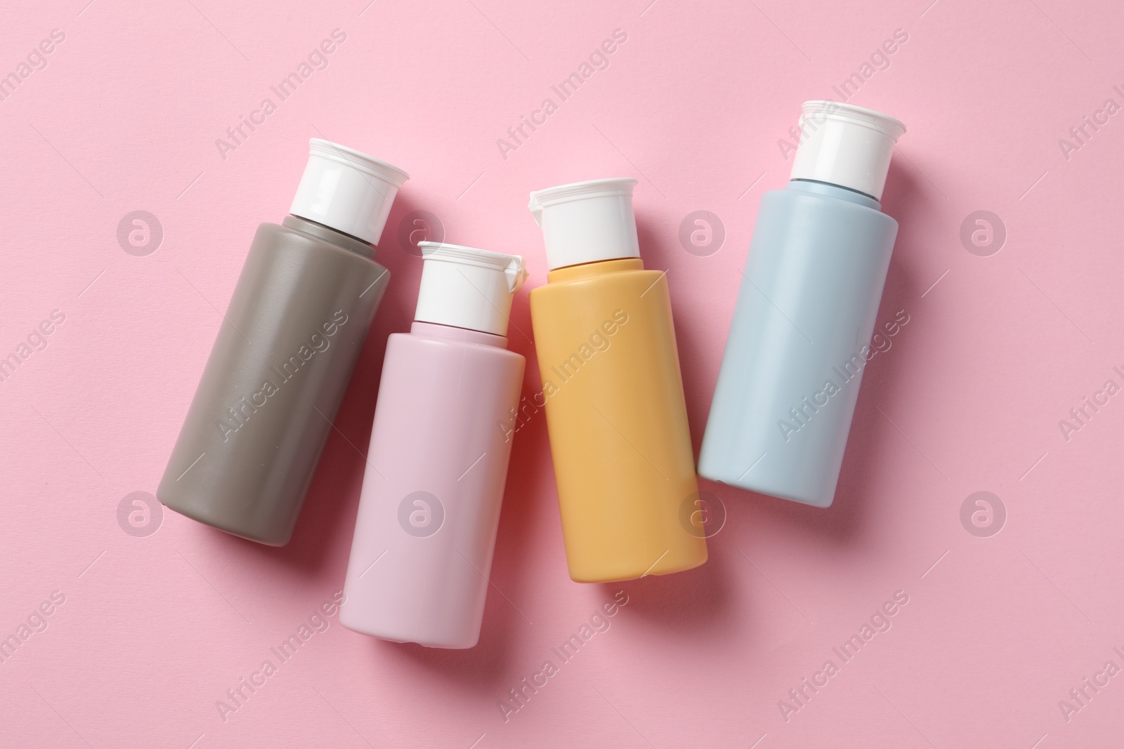 Photo of Cosmetic travel kit on pink background, flat lay. Bath accessories