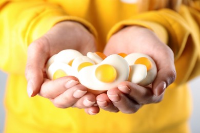 Photo of Woman holding handful of delicious gummy fried eggs shaped candies, closeup