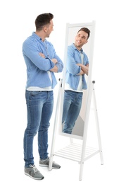 Photo of Young man looking at himself in mirror on white background