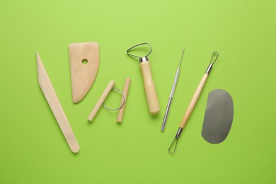 Photo of Set of clay modeling tools on green background, flat lay