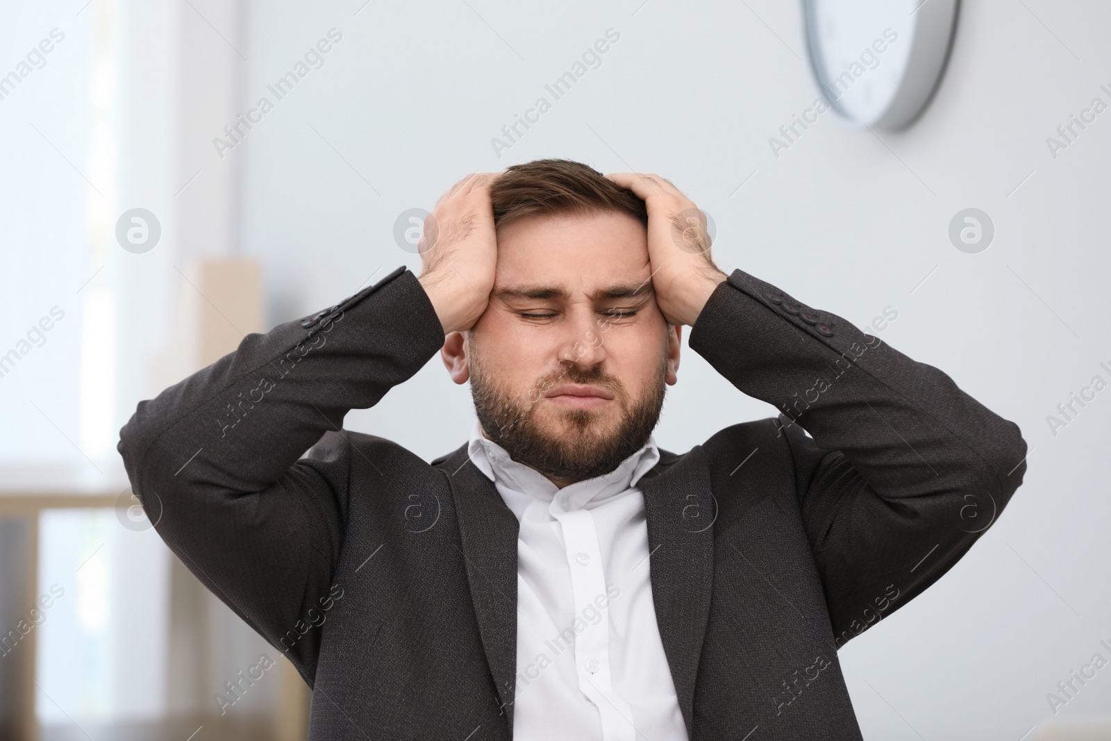 Photo of Young man suffering from migraine in office