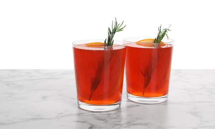 Photo of Aperol spritz cocktail, orange slices and rosemary in glasses on marble table against white background