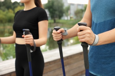 Photo of Couple practicing Nordic walking with poles outdoors, closeup