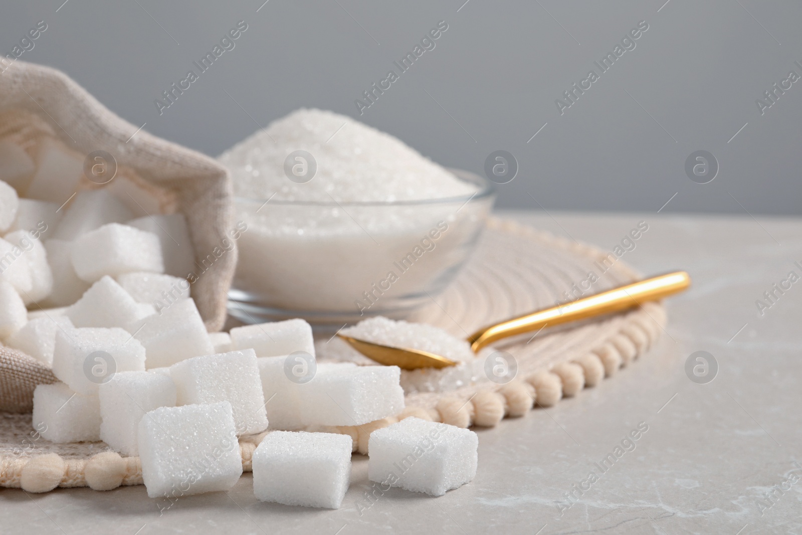 Photo of White sugar and wicker mat on light marble table, closeup. Space for text