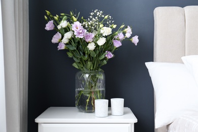 Photo of Bouquet of beautiful Eustoma flowers on nightstand in bedroom