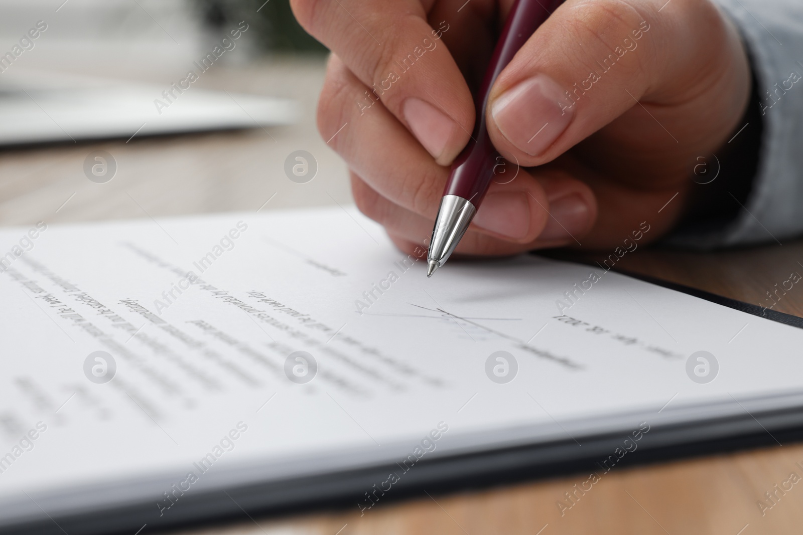 Photo of Man signing contract at table in office, closeup