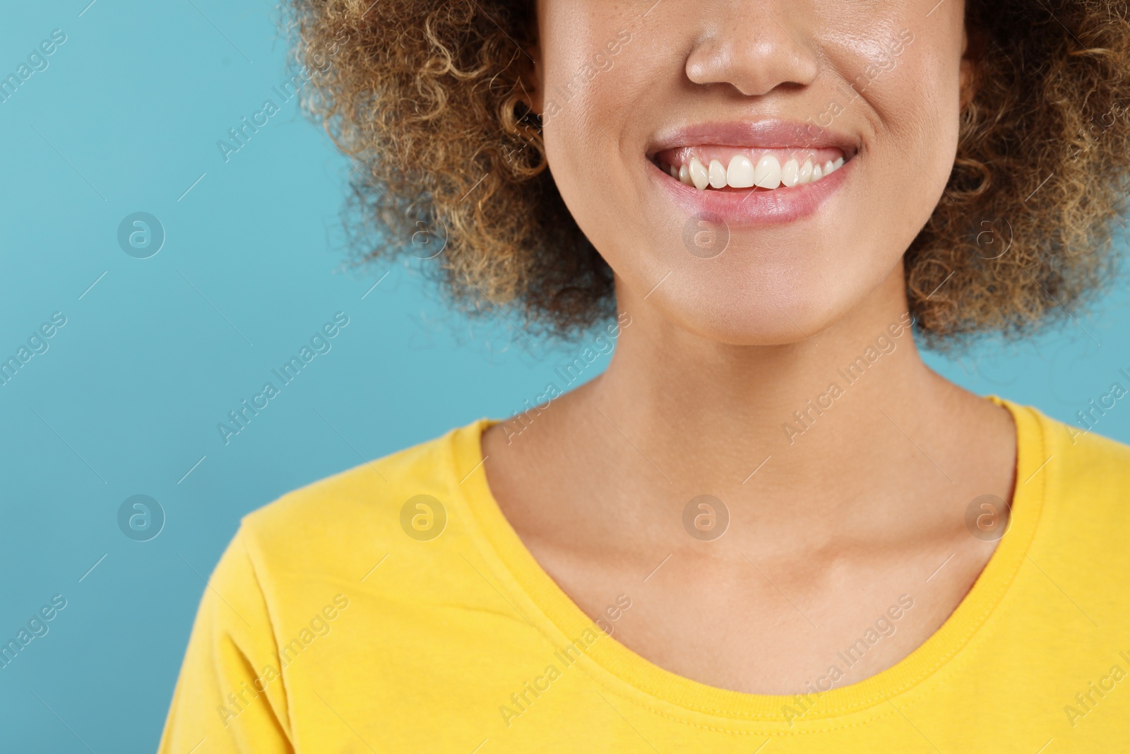 Photo of Woman with clean teeth smiling on light blue background, closeup