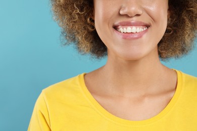 Photo of Woman with clean teeth smiling on light blue background, closeup