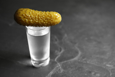 Photo of Cold Russian vodka with pickle on black table, closeup. Space for text
