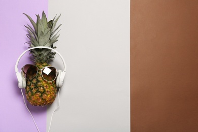 Funny pineapple with headphones and sunglasses on color background, top view. Space for text