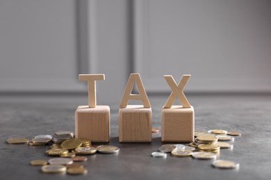 Photo of Word Tax, wooden letters and coins on grey table