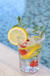 Photo of Delicious refreshing lemonade with raspberries near swimming pool