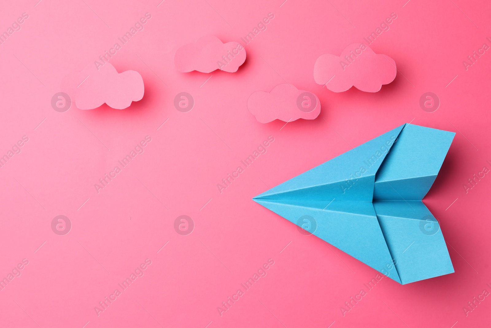 Photo of Handmade light blue paper plane with clouds on pink background, flat lay. Space for text