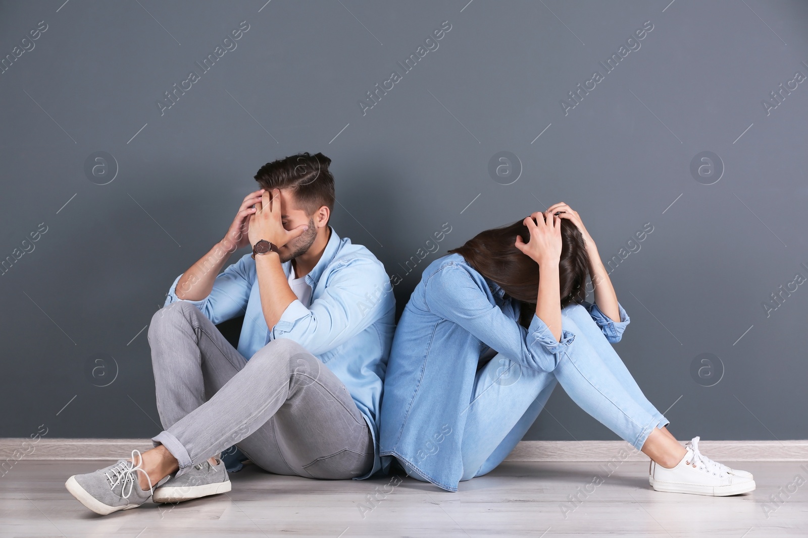 Photo of Upset young couple near grey wall. Relationship problems