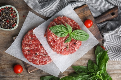 Flat lay composition with raw meat cutlets for burger on wooden table